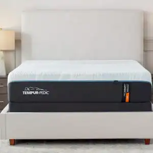 An elegant bedroom featuring a Tempur-Pedic TEMPUR-ProAdapt® 12" Firm mattress on a simple frame with a white headboard, flanked by two nightstands with lit lamps.