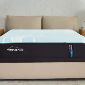 A Tempur-Pedic TEMPUR-LuxeAdapt® 13" Soft mattress sits atop a low-profile bed frame in a modern bedroom with beige walls, twin nightstands, and ambient lighting.