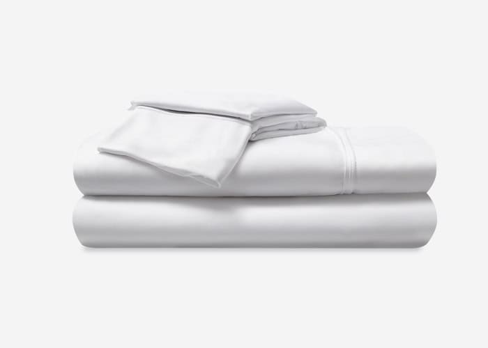 A set of neatly folded Dri-Tec bed sheets and pillowcases is stacked on a white surface. This set includes two pillowcases on top and larger sheets underneath, presenting an overall clean and crisp appearance.