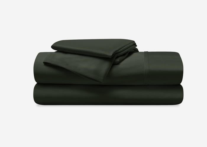 A neatly folded Dri-Tec Sheet Set in dark green, which includes two pillowcases, a flat sheet, and a fitted sheet, is stacked on top of each other against a plain white background. The sheets appear smooth and well-organized.