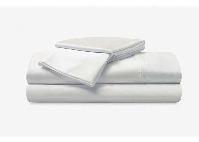 A neatly folded stack of the Hyper-Cotton Sheet Set is shown against a plain background. The set includes a fitted sheet, flat sheet, and two pillowcases, all crafted from pristine white fabric that creates a clean and minimalistic appearance.