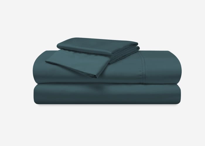 A neatly stacked Hyper-Cotton Sheet Set in dark teal, featuring a fitted sheet, flat sheet, and two pillowcases. Each piece is uniformly folded and the fabric appears smooth and well-pressed, emphasizing a clean and crisp appearance.