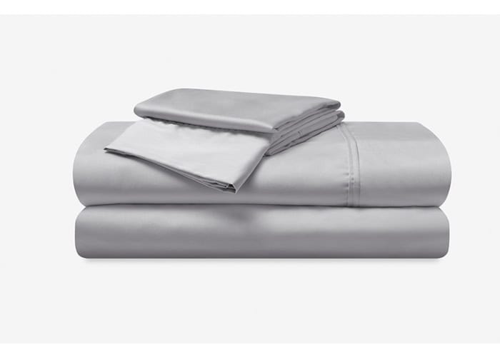 A neatly folded Hyper-Cotton Sheet Set, which includes a fitted sheet, flat sheet, and pillowcases, is arranged on a white background. The fabric has a smooth and silky appearance, suggesting a soft and luxurious texture ideal for premium bedding.