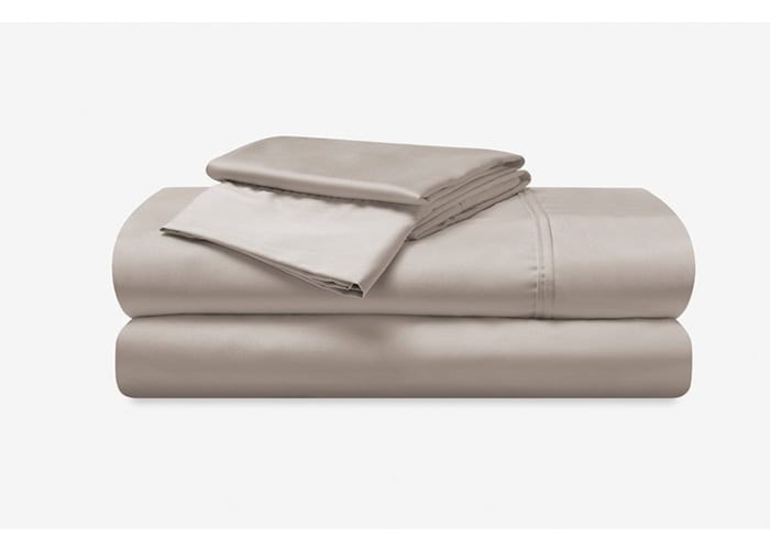 A neatly folded Hyper-Cotton Sheet Set in beige, featuring a fitted sheet, a flat sheet, and two pillowcases, arranged against a plain white background. The sheets boast a smooth, silky appearance.