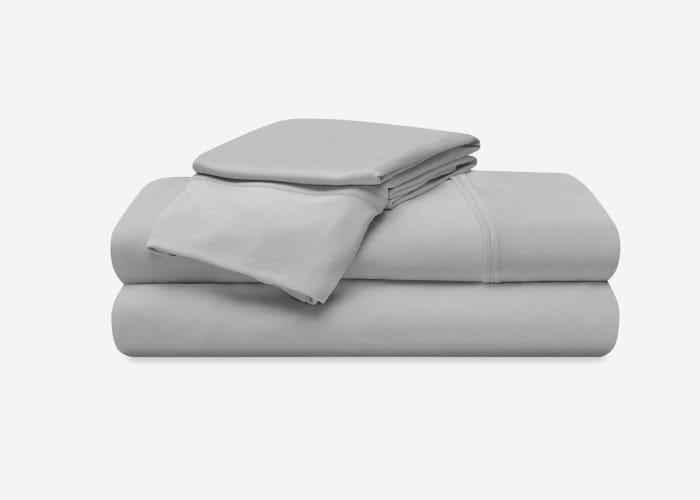 A neatly folded Ver-Tex Sheet Set, featuring a fitted sheet, flat sheet, and two pillowcases, is showcased against a plain white background. The gray bedding looks smooth and crafted from soft fabric, conveying a sense of comfort and coziness.