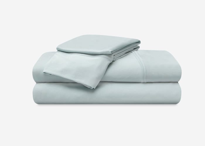 A neatly folded Hyper-Cotton Sheet Set (Copy) in light grey, including a flat sheet, fitted sheet, and pillowcases, is stacked on a white background.