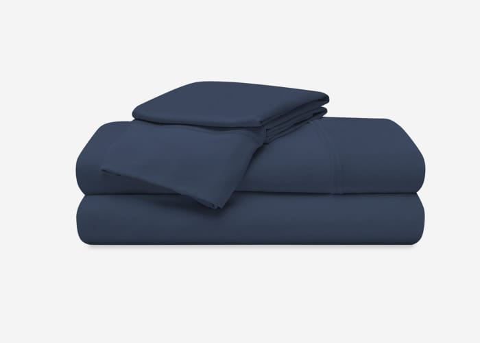 A neatly folded set of Hyper-Cotton Sheet Set (Copy) in dark blue, including a fitted sheet, a flat sheet, and two pillowcases, arranged in a stack on a plain white background.