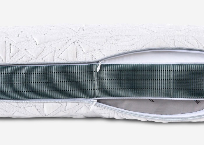 Close-up of a TEMPUR-Breeze® ProHi Pillow featuring a white, textured, geometric-patterned cover. The partially unzipped cover reveals a green ribbed inner layer.