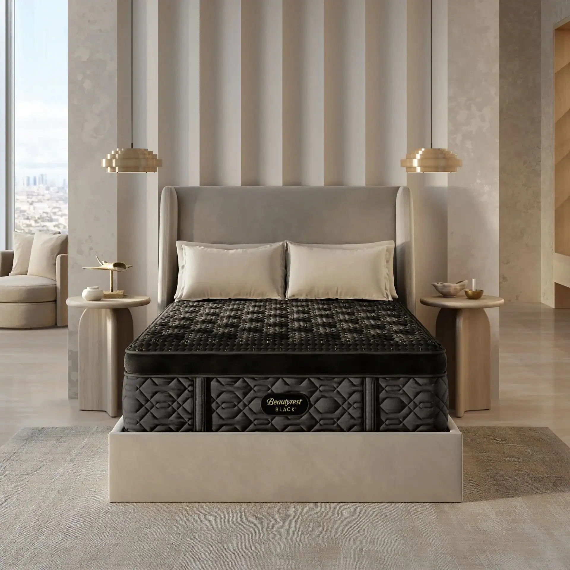 A modern bedroom with a large, upholstered bed featuring the Beautyrest Black® Series Four Medium Pillow Top mattress, cream pillows, matching nightstands, and neutral walls overlooking a city view through the window.