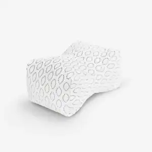 The Knee Pillow is white with a surface pattern of small gray oval loops and features ergonomic contours for comfortable use between the knees.