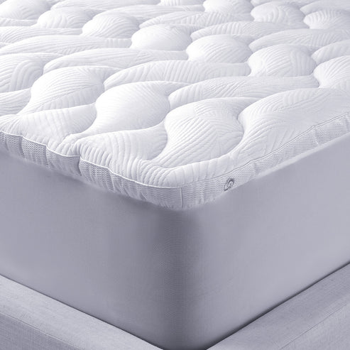 Close-up of a white, quilted mattress with a textured, leaf-patterned top and a plush React Pro Performance Mattress Topper for extra comfort. The thick mattress rests on a light-colored bed frame.