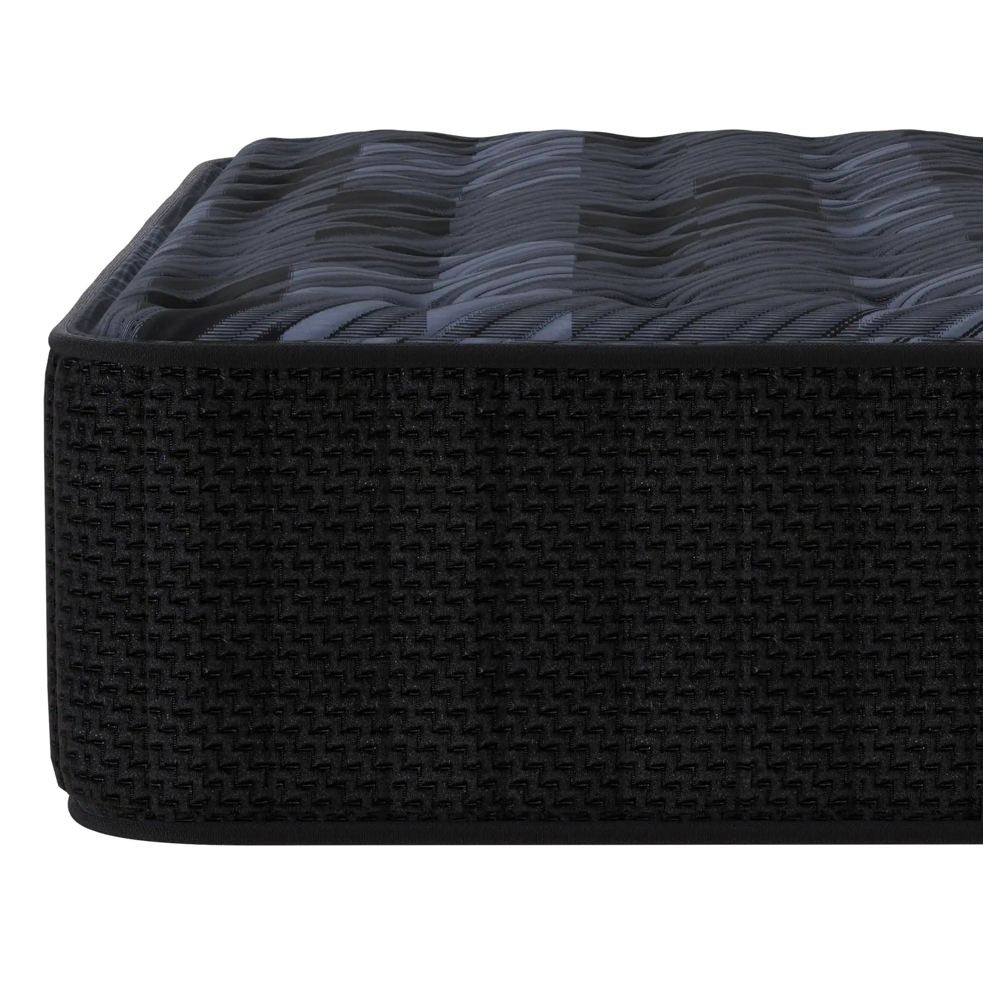 A close-up side view of Southerland's Pioneer Firm mattress highlights its textured black side fabric and wavy, dark-patterned top surface.