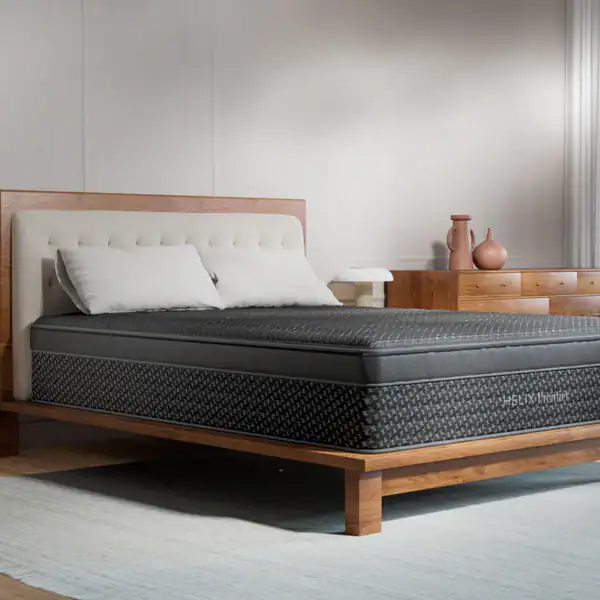 A modern bedroom with a wooden bed frame, tufted headboard, two white pillows, and a Helix Premier Plush Hybrid Mattress. A wooden dresser holds vases and a white lamp, all set on a light-colored rug.
