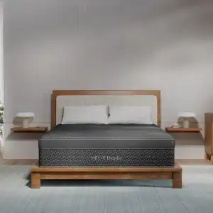 A modern bedroom with a wooden bed frame and a Helix Premier Plush Hybrid Mattress, plus white pillows, a headboard, two floating nightstands with lamps, and a light blue rug on the floor.