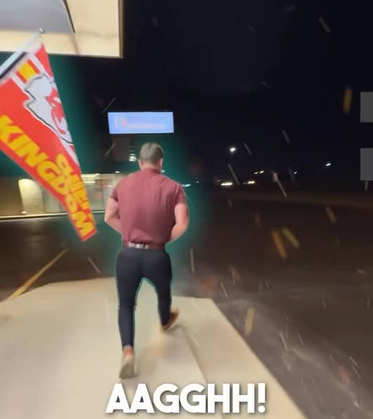 A person in a red shirt and dark pants runs outside at night near a Burger King sign, with a Kansas City Chiefs flag and "AAGGHH!" at the bottom&mdash;maybe they just heard about the Fall Savings Event for better sleep!.